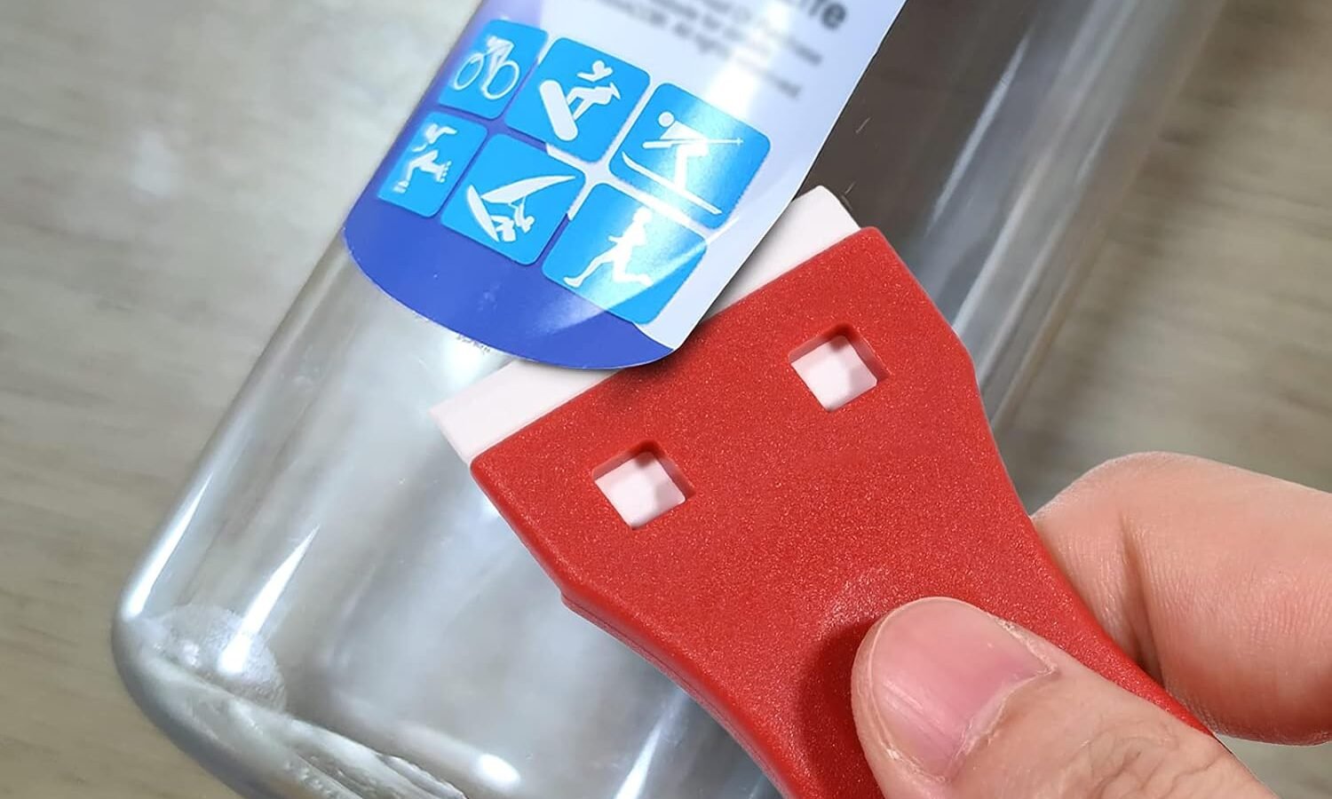 Glasflasche mit Etikettenrückständen steht auf einer ruhigen Arbeitsfläche.